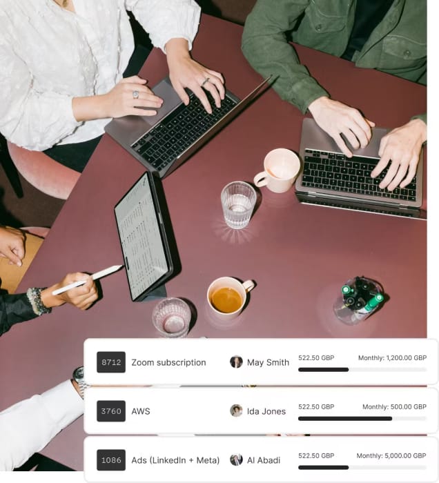 Three people sitting around a table, each working on a laptop. The table has drinks and office supplies. Below, a financial dashboard displays expenses for various services, listing subscriptions for Zoom, AWS, and Ads (LinkedIn + Meta), each assigned to different team members with corresponding monthly costs in GBP.